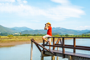 A young tourist looking at birds with spyglasses from the wooden piers of the Urdaibai marshes, a...