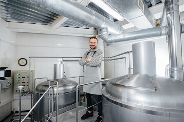 A young male brewer is engaged in the brewing process in a small brewery. Beer production.