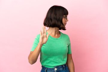 Young mixed race woman isolated on pink background making stop gesture and disappointed