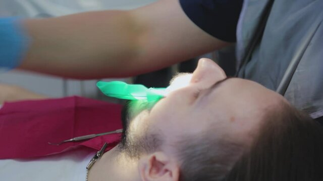 The dentist examines the patient's teeth with a special dental mirror. The guy at the dentist's appointment. 