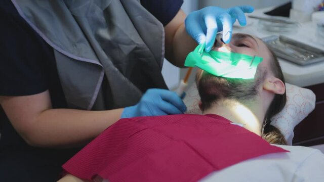 The dentist removes the patient's saliva with a special dental instrument. 