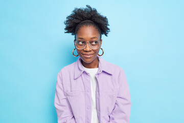 Portait of pensive satisfied dark skinned model has charming look focused away with dreamy...