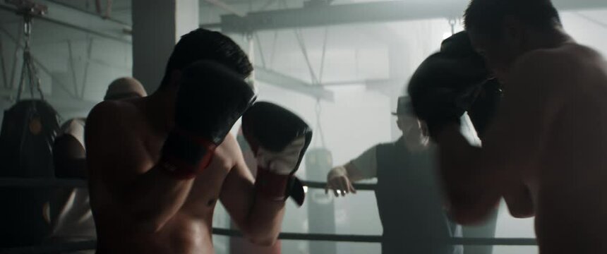 HANDHELD Two fighters having a kickboxing sparring fight, trainers watching. Dynamic cinematic footage. Shot with 2x anamorphic lens