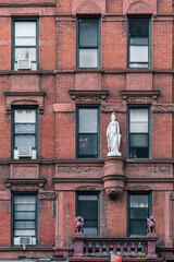 facade of old brick building with statue of woman