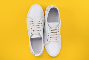 Fashionable white sneakers, sneakers on a colored yellow background, minimalism, top view, creative layout.
