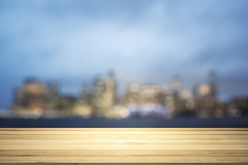 Blank table top made of wooden planks with beautiful blurry cityscape at twilight on background, mockup