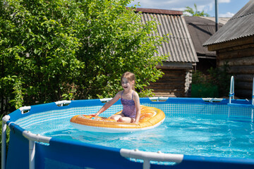 Cute little girl swims on beach air mattress in the pool