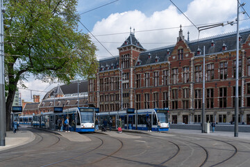 trams outside of the main station in downtown Amsterdam with commuters and people waiting