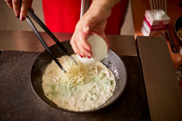 adds grated parmesan to the pasta, stirring in the pan with tongs