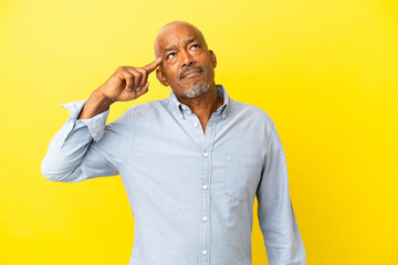 Cuban Senior isolated on yellow background making the gesture of madness putting finger on the head