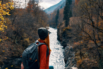 woman hiker with backpack near river mountains autumn forest travel