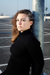 Fototapeta premium young brunette woman smoking a cigarette outdoors at a parking deck