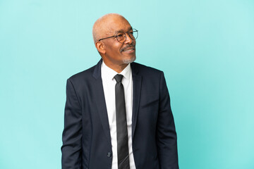 Business senior man isolated on blue background thinking an idea while looking up