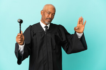 Judge senior man isolated on blue background making stop gesture