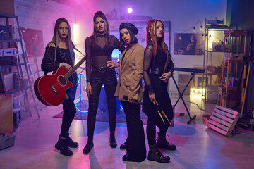 Fototapeta premium Group of young women with musical instruments standing in studio