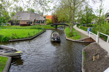 man steering a boat through the canals of Giethoorn village also known as Dutch Venice