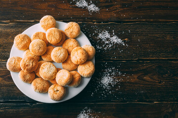 Homemade coconut rice flour cookies on a dark wooden background in a white plate. Copy space