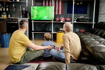 Rear view of family of three playing video game in living-room