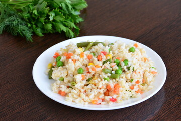 brown rice with vegetables and salad greens on the wooden kitchen table