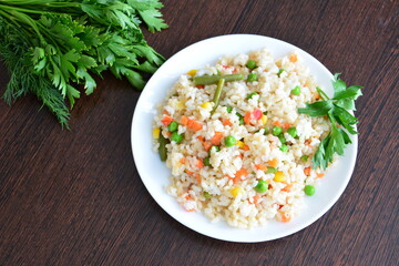 brown rice with vegetables and salad greens on the wooden kitchen table