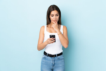 Young caucasian woman isolated on blue background thinking and sending a message