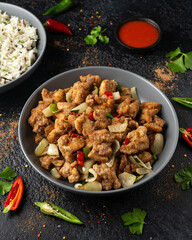 Stir fry chinese salt and pepper chicken with rice in grey bowl