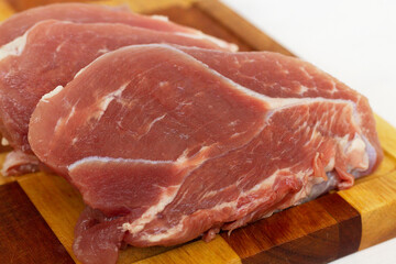 Close-up red steak on a cutting board. fresh slices of raw pork meat on a white background. copy space