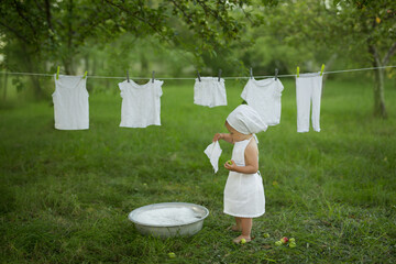 A child cheerfully launderes his clothes in the basin.Spray water and foam from washing clothes....