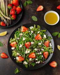 Asparagus and Strawberry Salad with vegetables, green peas and feta cheese in black plate. healthy food.