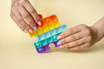 A woman holds a popular popit toy in her hands. Useful toys for the development of fine motor skills of the fingers. Anti-stress toy. entertaining games for children and adults. simple dimple.