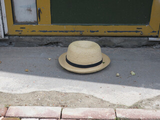 lost straw hat with a black ribbon on a sidewalk