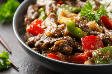 Stir fry Chinese pepper beef steak with onion, red and green bell pepper, rice in bowl