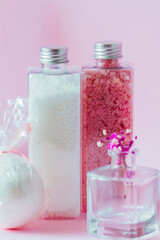 Bathroom accessories in containers close-up on a pink background.