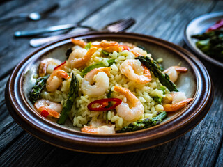 Risotto with prawns and asparagus on wooden background
