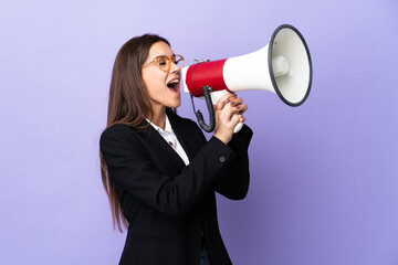 Business woman isolated on purple background shouting through a megaphone