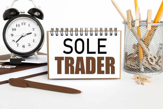 SOLE TRADER. a notebook on a work table, near a desk clock, a flowerpot and a glass with pencils