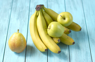 Bananas with apples and pears on a blue background, food benefits for health and diet, with copy space