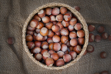 Hazelnuts in the basket against the background of a burlap sack, photo from above