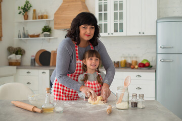 Family traditions, grandmother and granddaughter cook together in the kitchen, knead the dough