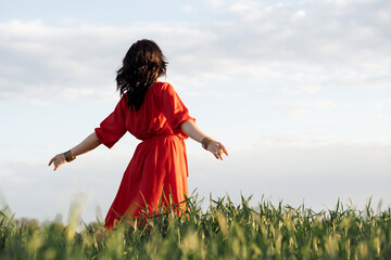beautiful hispanic young woman in red dress whirls in a field at sunset