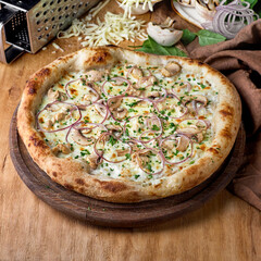 Pizza with chicken meat, mushrooms, cheese, onion, sauce on wooden background. Fast food lunch for picnic company