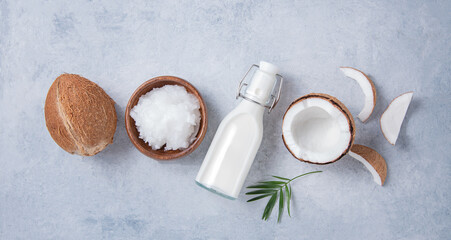 Healthy flat lay concept. Vegan milk bottles,coconut oil,  coconut slices and palm branch on blue background. Top  view and copy space