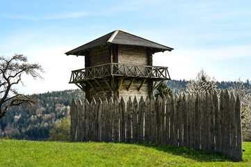 A reconstructed wooden Roman watchtower and a wooden border fence under a clear blue sky. This...