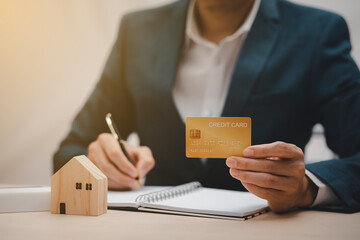 Businessman hand write note on paper with hold credit card with financial transaction with credit card and laptop computer, Online shopping concept, banking and online shopping at the home.