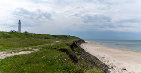 Fototapeta na wymiar panorama of the lighthouse and grassy sand dunes above the white sand beach at Hirtshals in northern Denmark