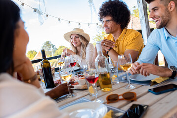 Group of friends at reunion eating and drinking wine.