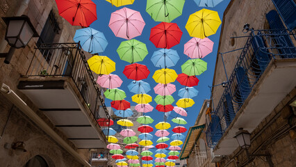 Street decorated with colored umbrellas. Multicolored parasols above narrow pedestrian street of the old city.