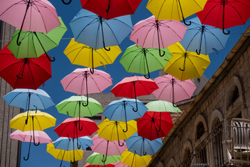 Street decorated with colored umbrellas. Multicolored parasols above narrow pedestrian street of the old city.