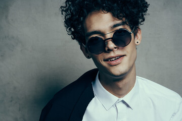 Fototapeta premium portrait of a curly-haired guy in a shirt with a jacket on his shoulder and glasses on his face close-up 
