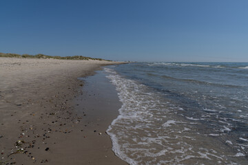 idyllic golden sand beach in northern Denmark with sand dunes and gentle waves lapping at the shore